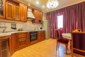 a kitchen with wooden cabinets and a table and a dining room at FiveStars Kuban in Krasnodar