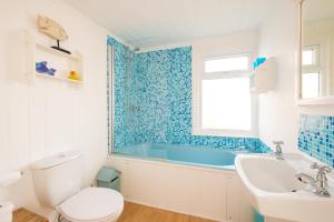 a bathroom with a tub and a toilet and a sink at Shore Cote, Thorpeness in Thorpeness +23 photos