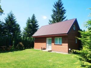 una pequeña casa en un patio con un campo de hierba en Domki Całoroczne - Tarlagowy Bór, en Bebło