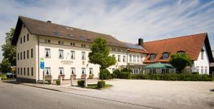 un grand bâtiment blanc avec un toit marron dans l'établissement Gasthaus Landbrecht, à Freising