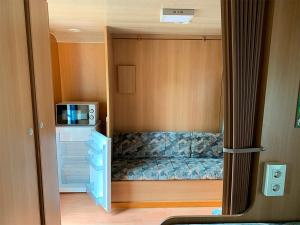 Habitación pequeña con cama y microondas. en Camping Santa Tecla, en A Guarda
