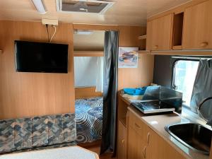una pequeña cocina con TV en una caravana en Camping Santa Tecla, en A Guarda