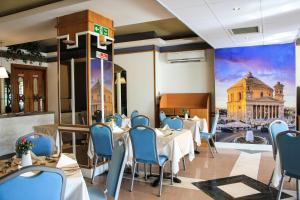 a restaurant with tables and chairs and a mural of a building at Coral Hotel in St Paul's Bay