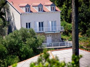 une maison avec un toit rouge et un balcon dans l'établissement Apartments Nodilo, à Polače