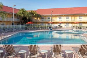 a swimming pool with chairs and a hotel at La Quinta Inn by Wyndham Cocoa Beach-Port Canaveral in Cocoa Beach