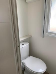 a white toilet in a bathroom with a window at Villa Granja Sol in São Félix da Marinha