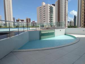 a swimming pool on top of a building with tall buildings at Essencial Manaíra in João Pessoa