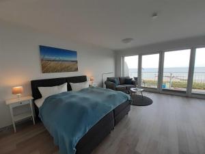 ein Schlafzimmer mit einem Bett, einem Sofa und Fenstern in der Unterkunft Strandappartements Haus Strandkieker in Schönhagen