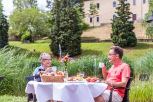 Dois homens sentados numa mesa com comida e bebidas. em Hotel am Schloß Apolda em Apolda