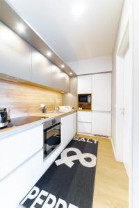 una cocina con armarios blancos y una alfombra negra en el suelo en Apartment Monochrome Urban Hoodie, en Liubliana