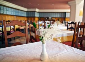 a white vase with flowers sitting on a table at Hotel Apartamentos Trevenque in Sierra Nevada