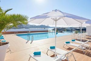 ein Pool mit Stühlen und einem Sonnenschirm neben einem Pool in der Unterkunft Calanova Sports Residence in Palma de Mallorca