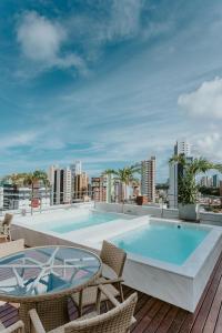 a pool on the roof of a building with chairs at Guest Manaíra Apart Hotel in João Pessoa