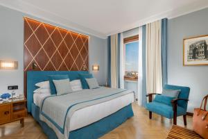 1 dormitorio con 1 cama grande y 1 silla azul en Bettoja Hotel Mediterraneo, en Roma