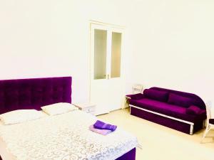 リヴィウにあるAnna Apartmentsのベッドルーム(ベッド1台、紫色のソファ付)