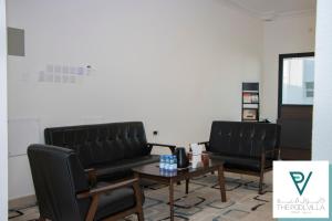 a living room with two black leather chairs and a table at THE POOL VILLA - TANUF in Nizwa