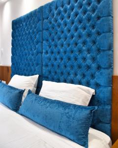 - une tête de lit capitonnée bleue avec des oreillers sur un lit dans l'établissement Lycabettus Exclusive Apartments, à Athènes