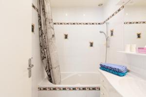 ein weißes Bad mit einer Badewanne und einer Dusche in der Unterkunft Violet, bord de mer in Cannes