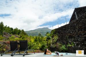 une femme assise dans un bain à remous à côté de deux chaises dans l'établissement Casas do Amarelo, à São Mateus