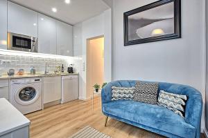 uma sala de estar com um sofá azul e uma cozinha em Graça 4 em Lisboa