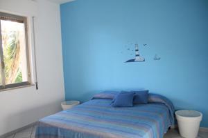 Dormitorio azul con cama y ventana en Sottovento, en Marina di Modica