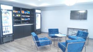 uma sala de espera com cadeiras azuis e uma televisão em Magnolia Inn and Suites Olive Branch em Olive Branch