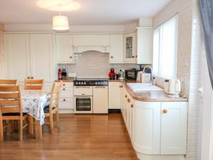 a kitchen with white cabinets and a table with a dining room at River Cottage in Newry