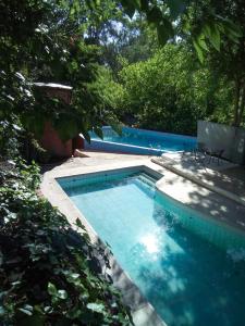 a swimming pool with two chairs and trees at Cabañas El Challao in Mendoza