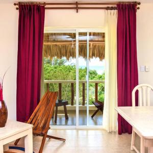 a living room with red curtains and a sliding glass door at Los Depas del Aeropuerto Holbox in Holbox Island