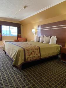 a hotel room with a large bed with white pillows at Americas Best Value Inn - Azusa/Pasadena in Azusa