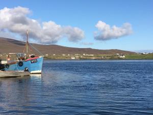 un barco azul sentado en un gran cuerpo de agua en Achill Alantic Dream en Derreen