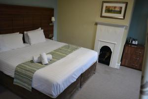 a bedroom with a large bed with a fireplace at Quorn Grange Hotel in Loughborough