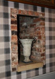 um vaso sentado numa prateleira numa lareira de tijolos em The Bell em Shifnal