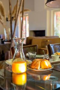 a glass jug of orange juice next to a plate of bread at Quinta do Ameal - Wine & Tourism Terroir in Refoios do Lima