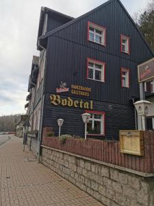 um edifício preto com um sinal na lateral em Harzbaude - Pension Gasthaus Bodetal em Rübeland