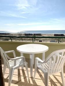 uma mesa branca e duas cadeiras numa varanda com praia em Apartamentos Guadiana em Monte Gordo