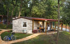 a stone cabin with people sitting at a table at Aminess Maravea Camping Resort Mobile Homes in Novigrad Istria