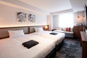 a hotel room with two beds and a couch at HOTEL FORZA HAKATAEKI CHIKUSHIGUCHI Ⅱ in Fukuoka