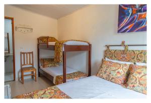 a bedroom with two bunk beds and a chair at Pousada Cravo e Canela in Arraial d'Ajuda