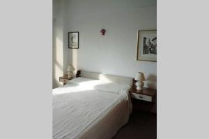 1 dormitorio con cama blanca y mesa con lámpara en Confortable 2 ambientes, excelente ubicación en Miramar