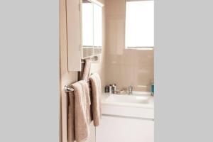 ein Badezimmer mit einer Badewanne, einem Waschbecken und Handtüchern in der Unterkunft The Smiths Self Catering Cottage in Kapstadt