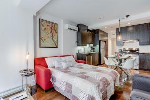 a bedroom with a red couch and a kitchen at Les Immeubles Charlevoix - Le 1174 in Quebec City