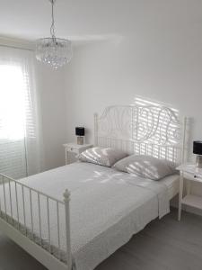 ein weißes Schlafzimmer mit einem weißen Bett und einem Kronleuchter in der Unterkunft Apartments Mirko&Ana in Bibinje