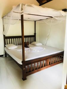 a wooden bed with a canopy in a room at King's Elephant Cabanas & Restaurant in Tangalle
