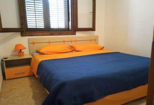 um quarto com uma cama com almofadas laranja e uma janela em La Veranda Sul Mare em Tre Fontane