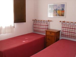 two beds in a room with red sheets and a table at VILLETTA SUL MARE, PANORAMICA in Villaputzu