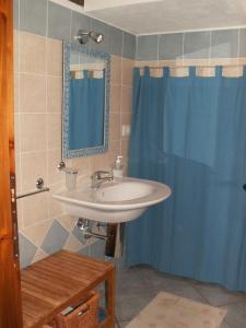 a bathroom with a sink and a blue shower curtain at VILLETTA SUL MARE, PANORAMICA in Villaputzu