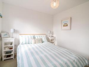 a white bedroom with a striped bed and two night stands at Ripple in Bodmin