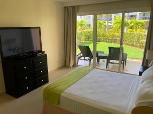 1 dormitorio con 1 cama, TV y patio en Beautiful One Bedroom unit with pool and Beach club in a Golf Project, en Punta Cana