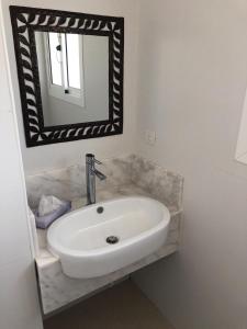 ein Badezimmer mit einem weißen Waschbecken und einem Spiegel in der Unterkunft Beautiful One Bedroom unit with pool and Beach club in a Golf Project in Punta Cana